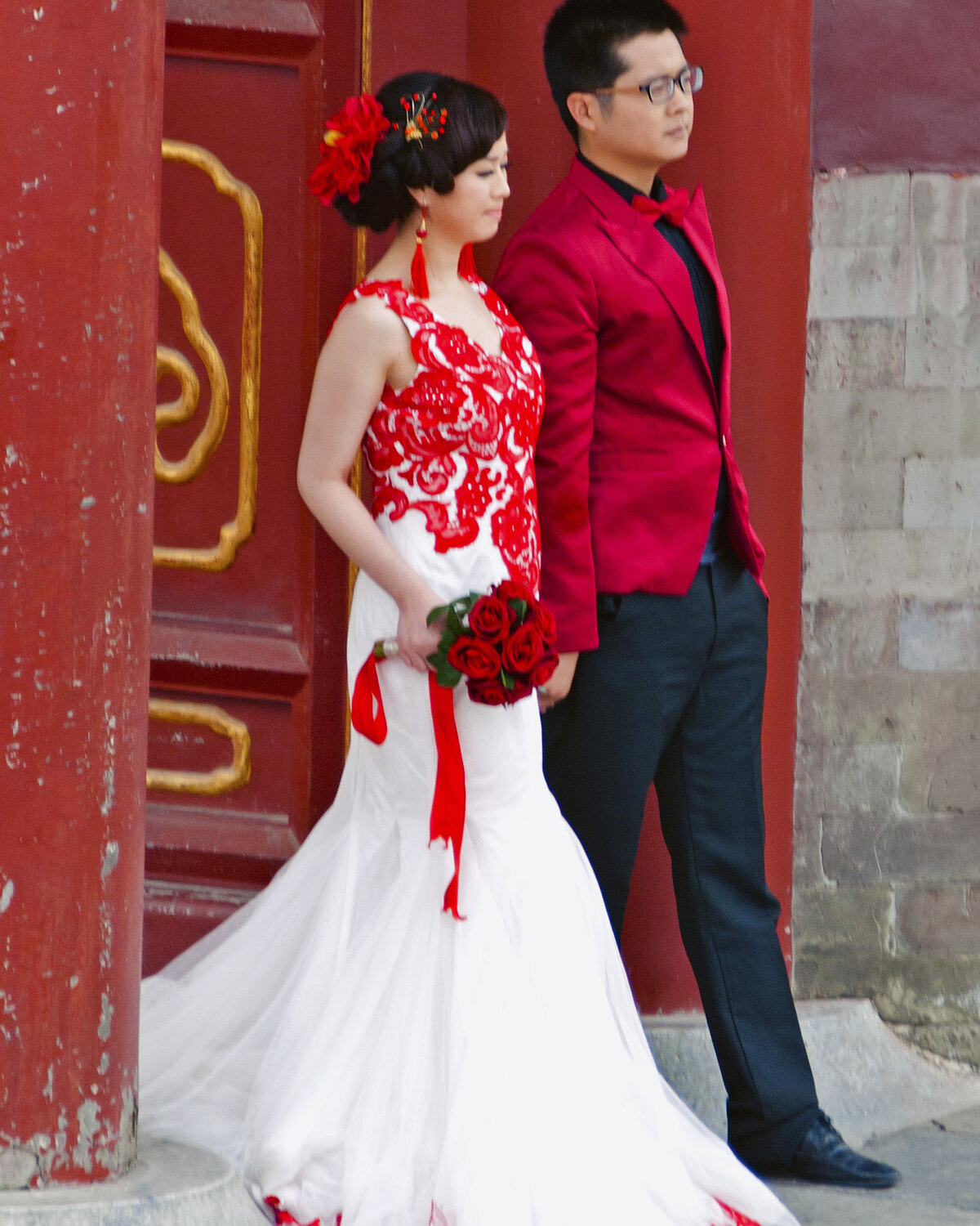A couple in wedding dress and black tie photographed against a carved screen